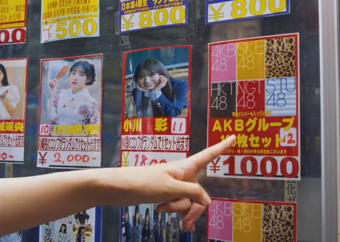 Shizuka pointing at the 100 card set on an AKB48 idol group card vending machine.